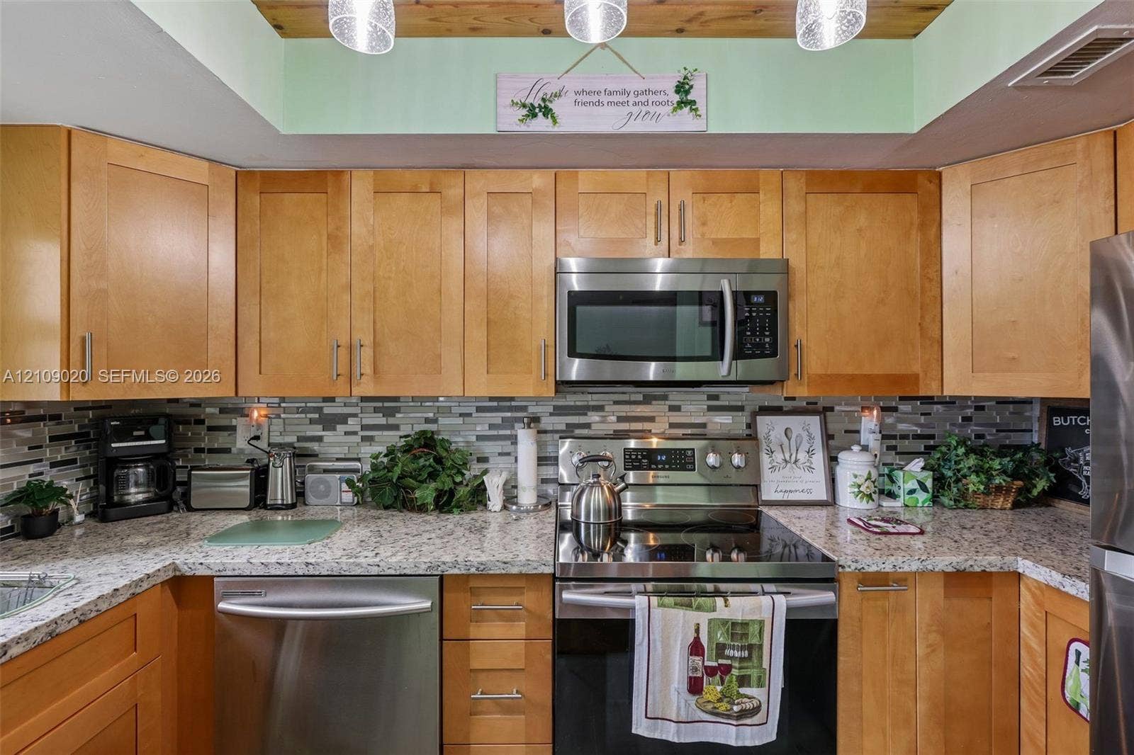701 NW 19th Street, #300, Fort Lauderdale, FL 33311 Kitchen featuring natural wood cabinetry, stone-patterned countertops, stainless steel appliances, multi-tonal linear tile backsplash, and wood-paneled tray ceiling
