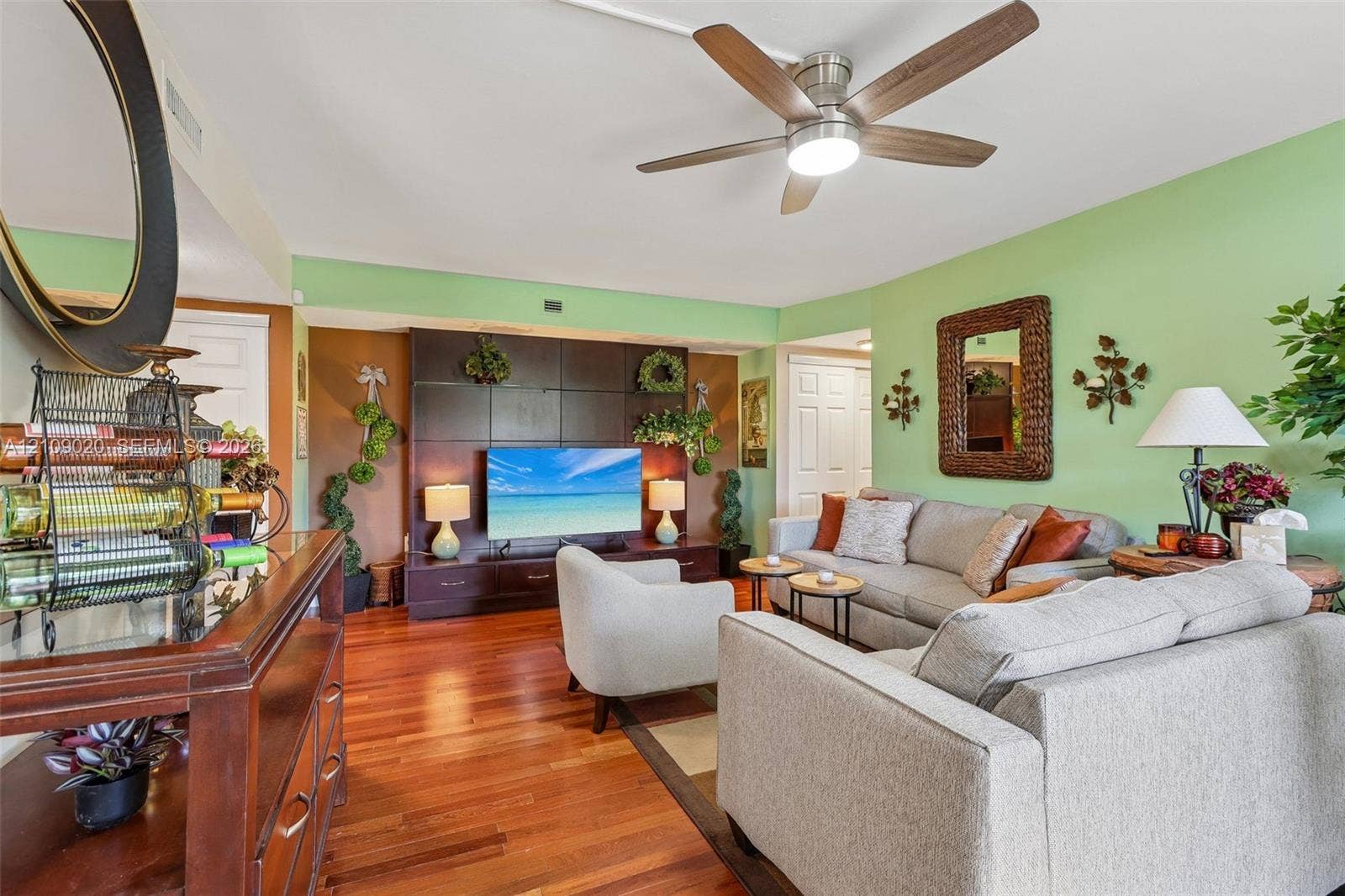 701 NW 19th Street, #300, Fort Lauderdale, FL 33311 Living area featuring wood-finish flooring, a ceiling fan with integrated lighting, and a dark-toned custom built-in entertainment center