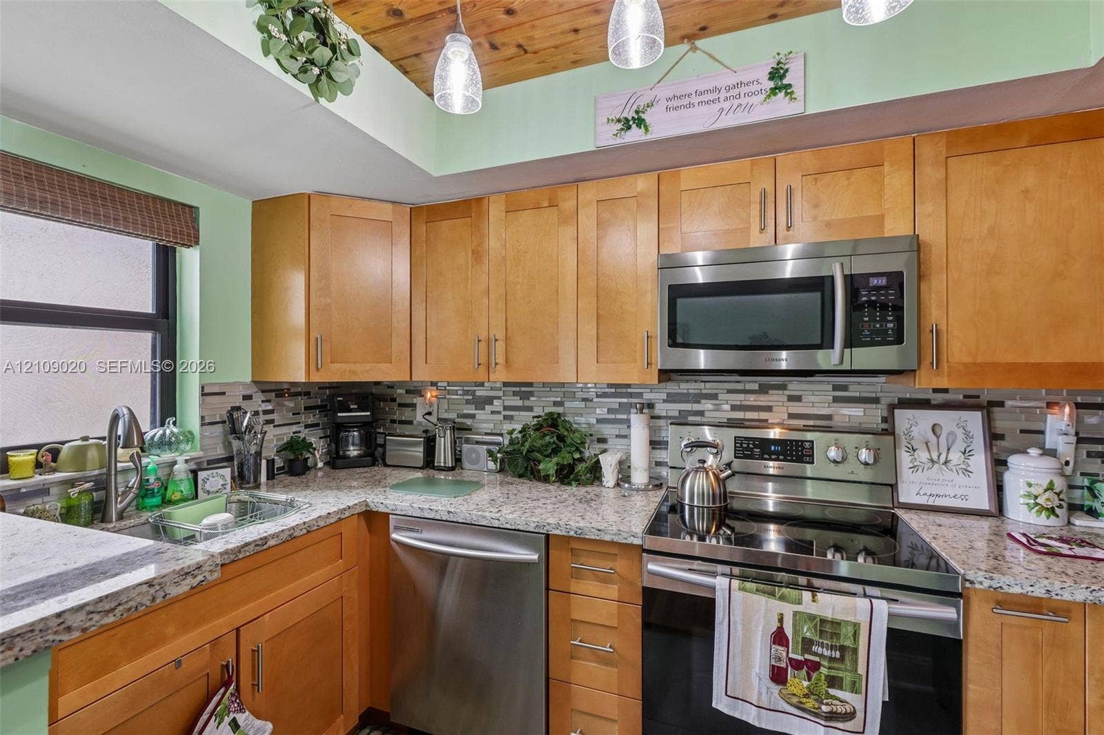 701 NW 19th Street, #300, Fort Lauderdale, FL 33311 Kitchen featuring natural wood cabinetry, stone-finish countertops, stainless steel appliances, multi-toned tile backsplash, and wood-paneled ceiling with pendant lighting