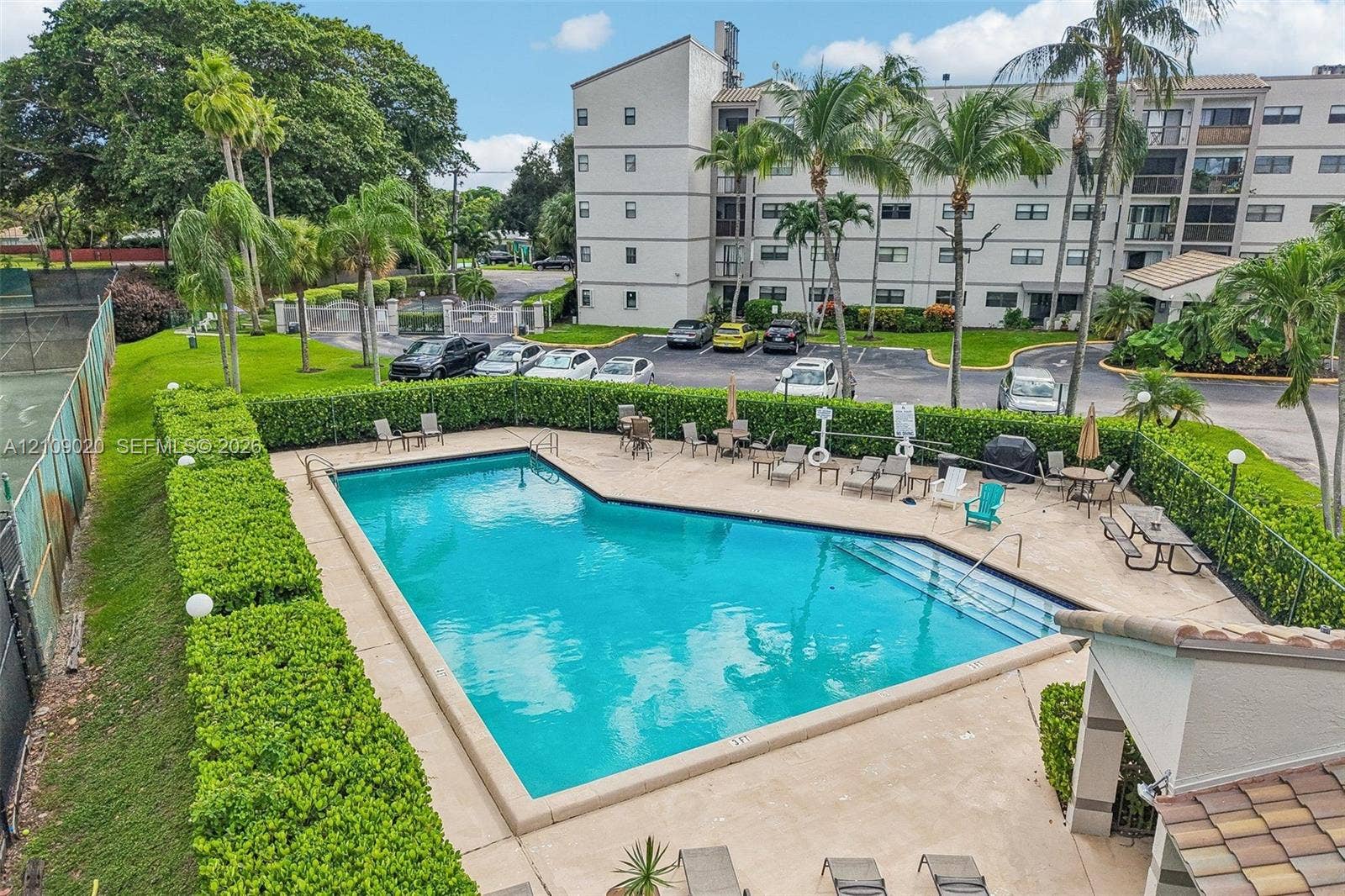701 NW 19th Street, #300, Fort Lauderdale, FL 33311 In-ground swimming pool featuring a concrete deck and perimeter hedge landscaping, inclusive of a tennis court facility