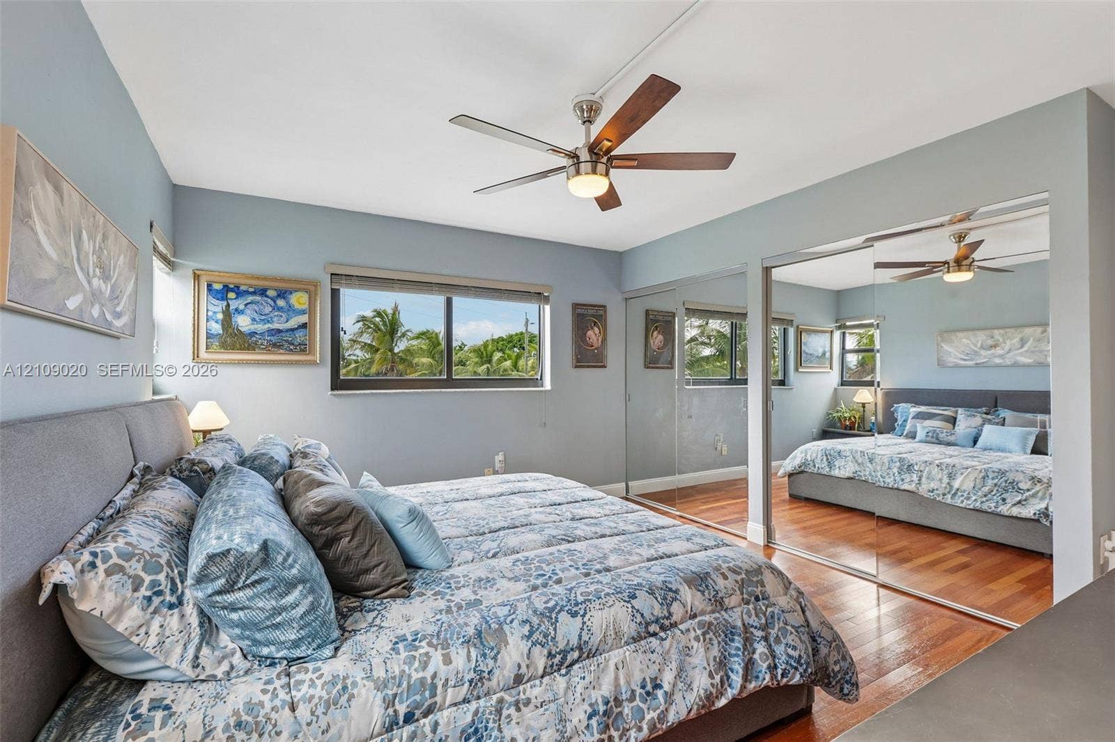 701 NW 19th Street, #300, Fort Lauderdale, FL 33311 Bedroom featuring wood-finish flooring, sliding mirrored closet doors, ceiling fan with integrated lighting, and horizontal windows