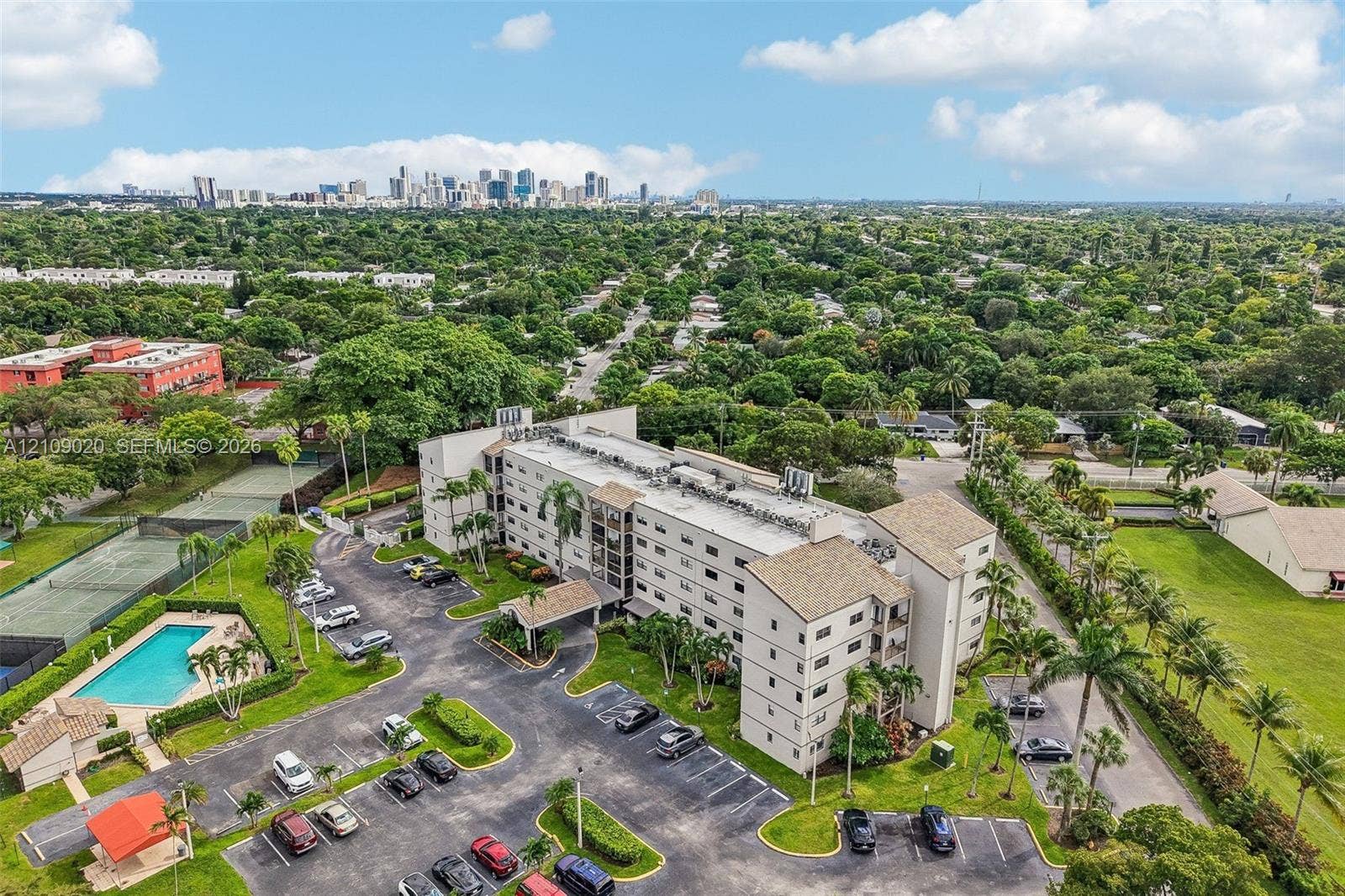 701 NW 19th Street, #300, Fort Lauderdale, FL 33311 Multi-story residential complex featuring surface parking, an outdoor swimming pool, and dedicated tennis courts, set within a landscaped perimeter