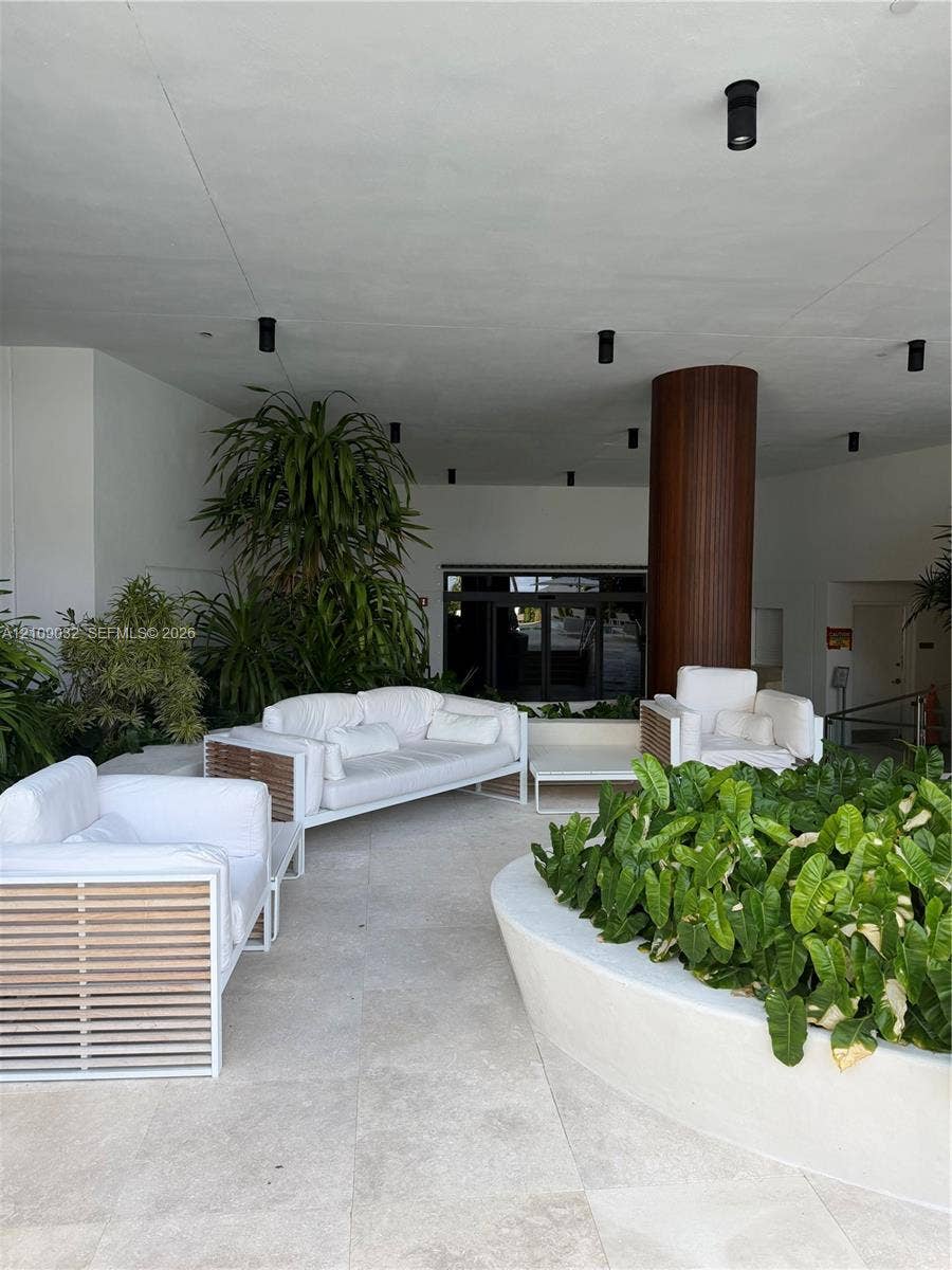 Covered patio area featuring large-format stone flooring, recessed ceiling lighting, a curved built-in planter, and a wood-paneled structural column