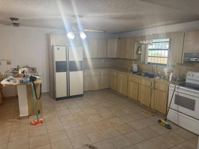 Kitchen featuring light-finish cabinetry, neutral tile flooring, built-in breakfast bar, and stainless steel sink
