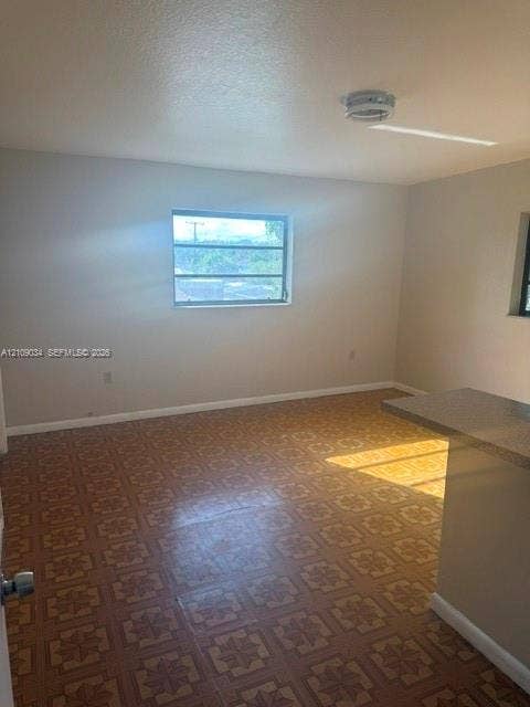 Interior room featuring patterned resilient flooring, neutral wall paint, a multi-pane window, and a built-in counter surface with a textured finish