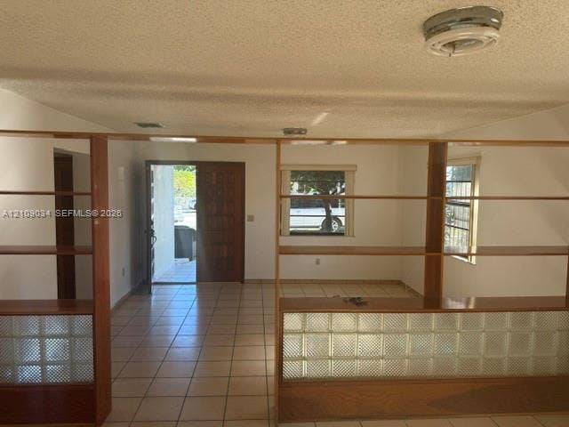 Interior area featuring tile flooring, built-in wooden shelving units, and glass block accents