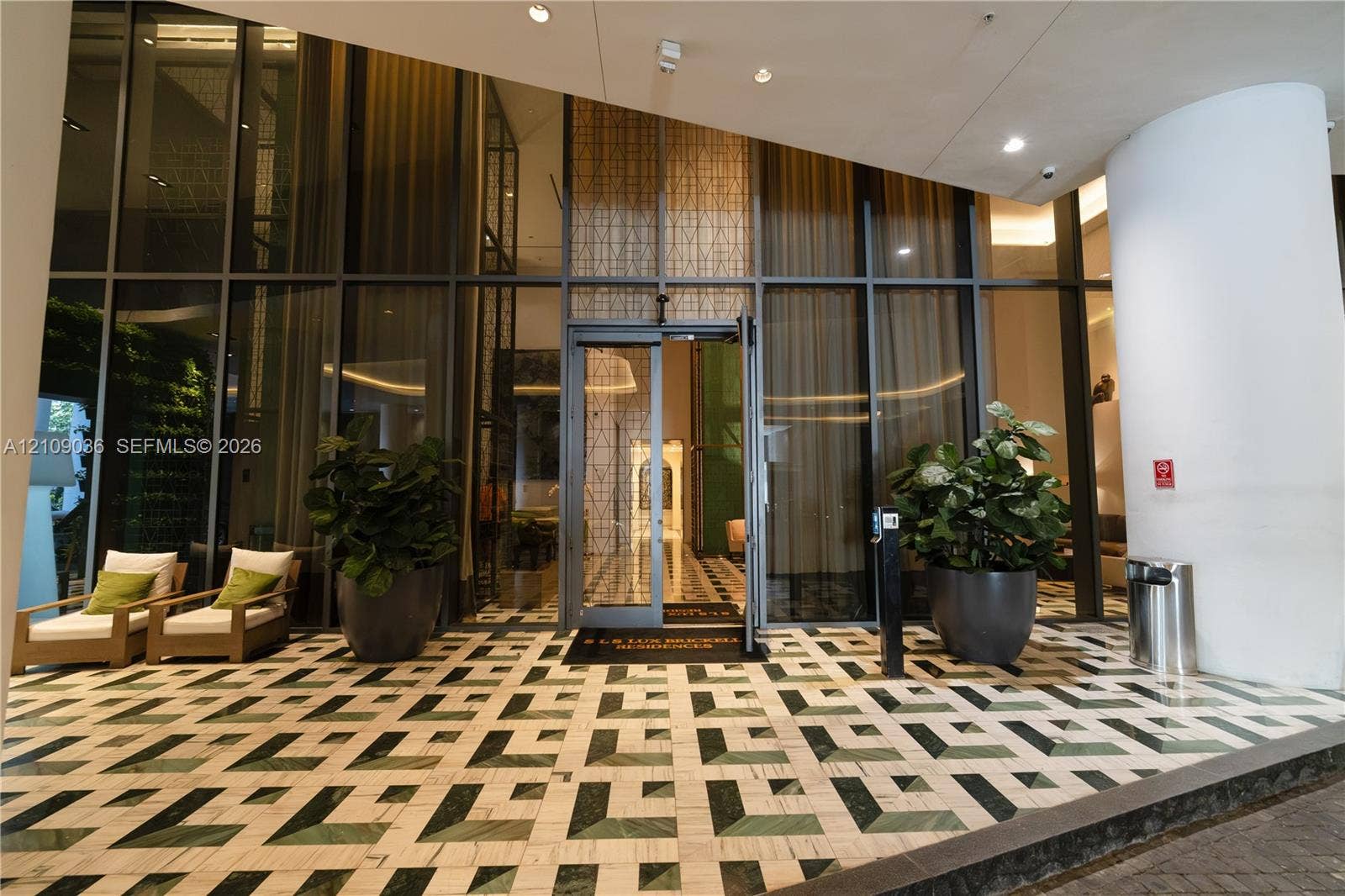 Grand entrance featuring floor-to-ceiling glass paneling, geometric stone tile flooring, and integrated recessed lighting