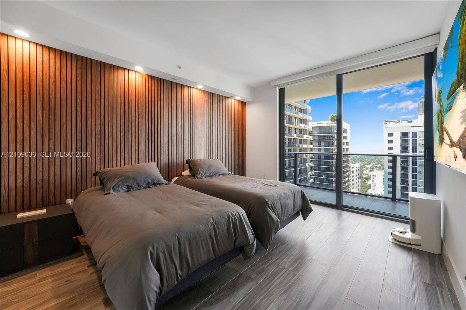 Floor-to-ceiling windows, wood-finish slat accent wall, recessed lighting, and balcony access with urban scenery