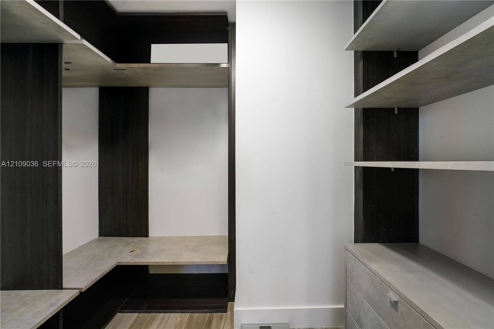 Custom built-in storage system featuring dark wood-tone cabinetry, multiple open shelving tiers, integrated drawer units, and light-toned horizontal surfaces