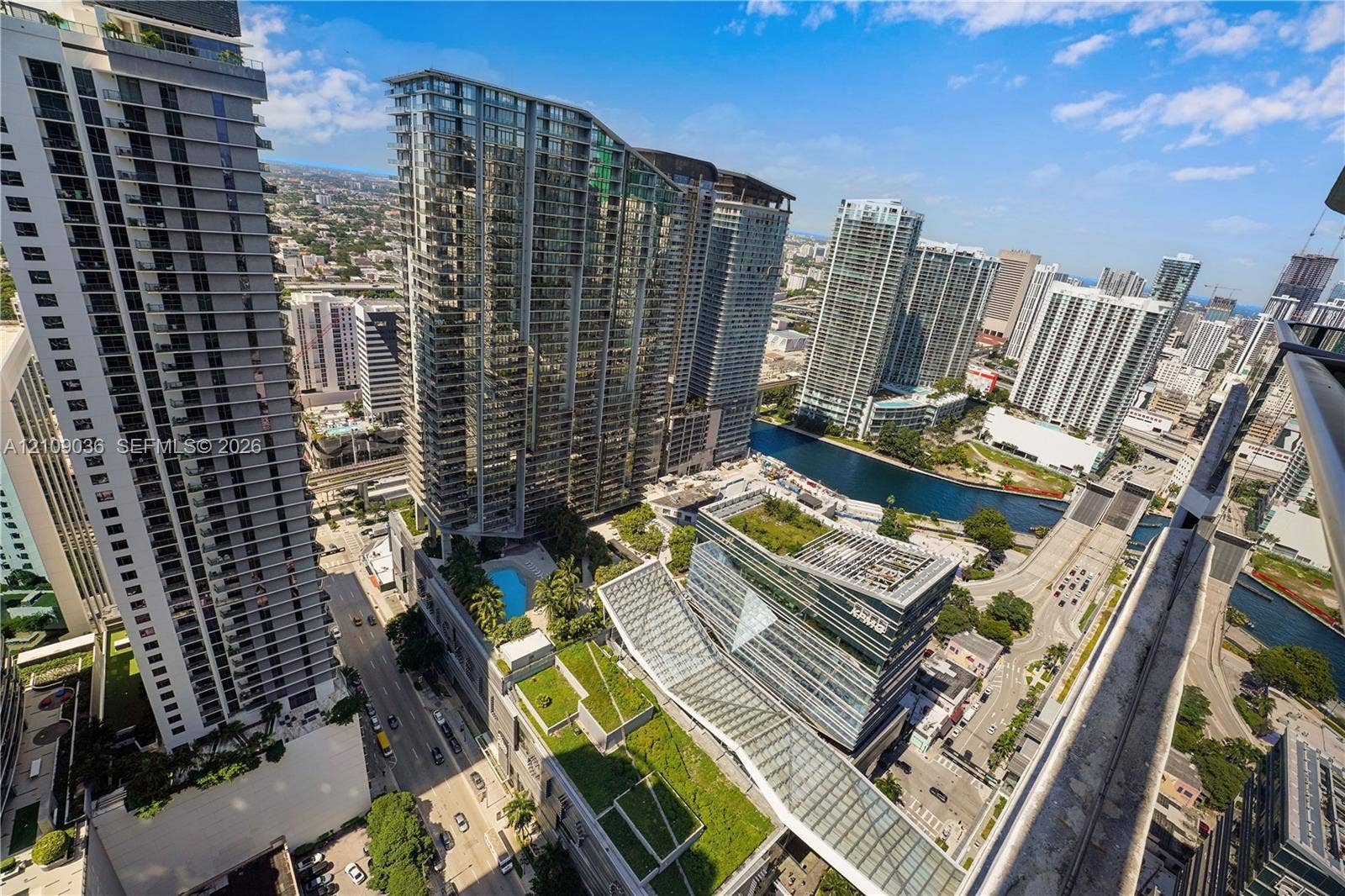 High-rise perspective featuring an outdoor swimming pool, landscaped green roofs, glass-facade architecture, and water frontage