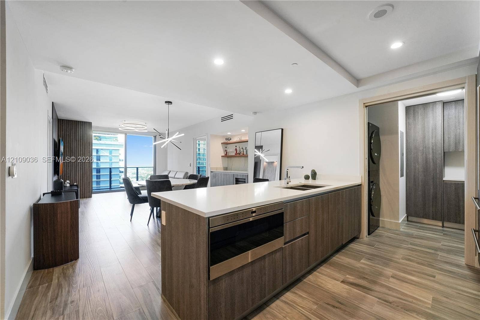 Kitchen island featuring white countertops, wood-finish cabinetry, built-in microwave, and recessed lighting