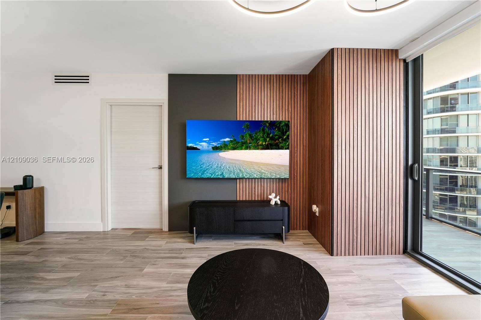 Interior featuring wood-finish flooring, floor-to-ceiling slatted wood wall paneling, and an expansive sliding glass door system