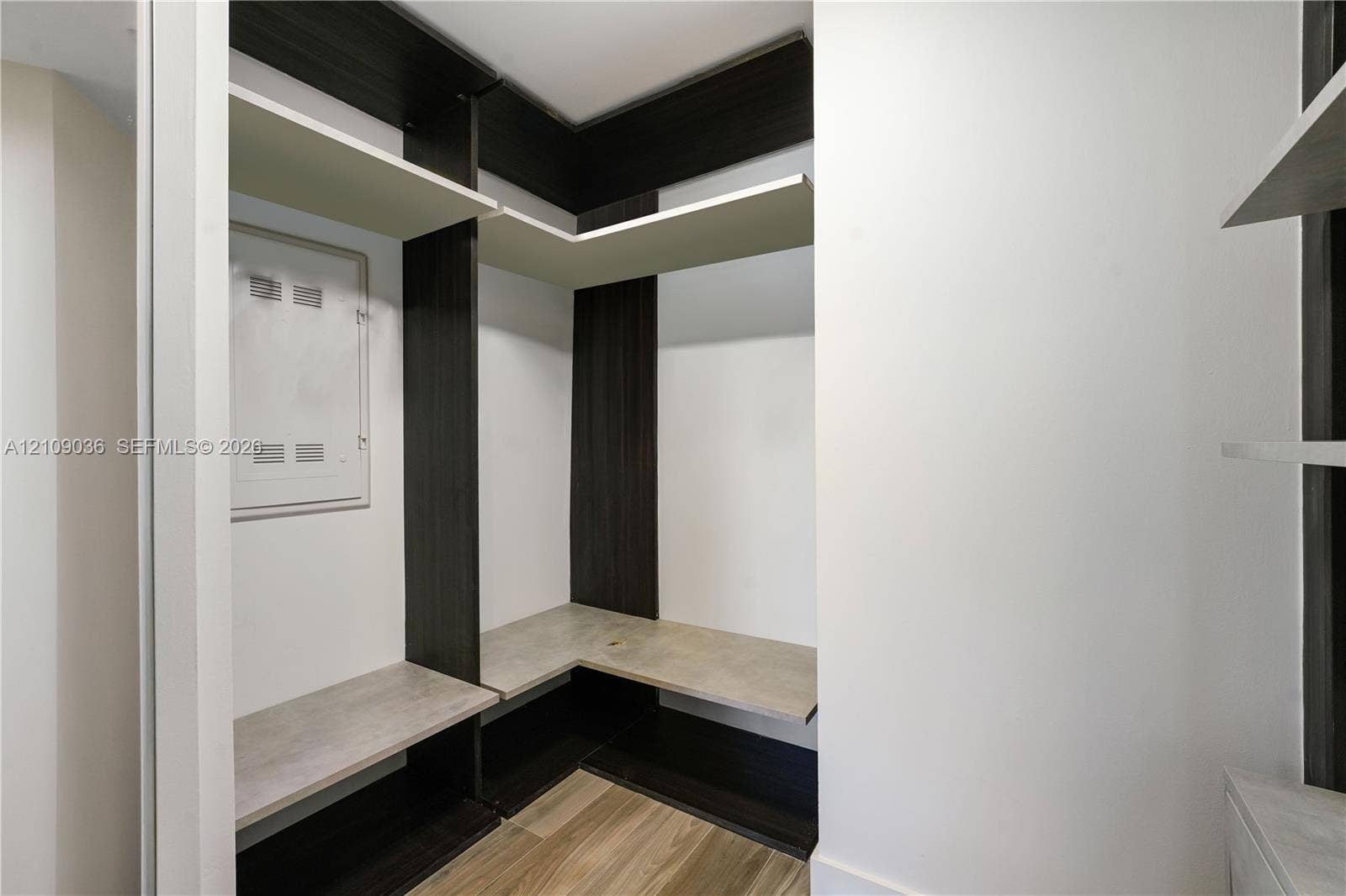 Built-in storage system featuring dark-finish vertical shelving, wood-finish flooring, and stone-finish horizontal shelving surfaces