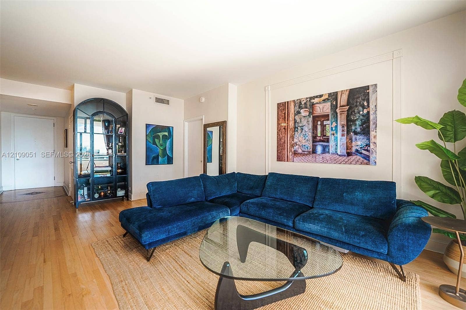 Interior space featuring wood-finish flooring, recessed decorative wall molding, and a built-in arched glass display cabinet