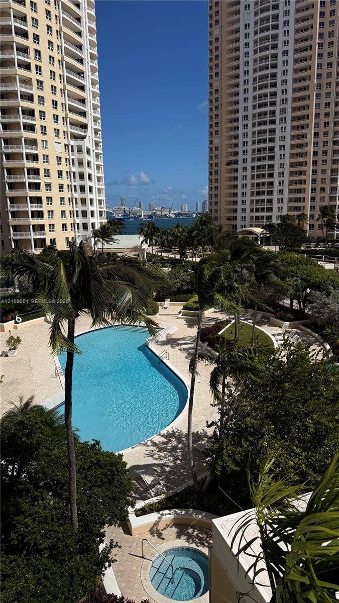 Outdoor swimming pool and spa surrounded by stone decking, palm trees, and mature landscaping