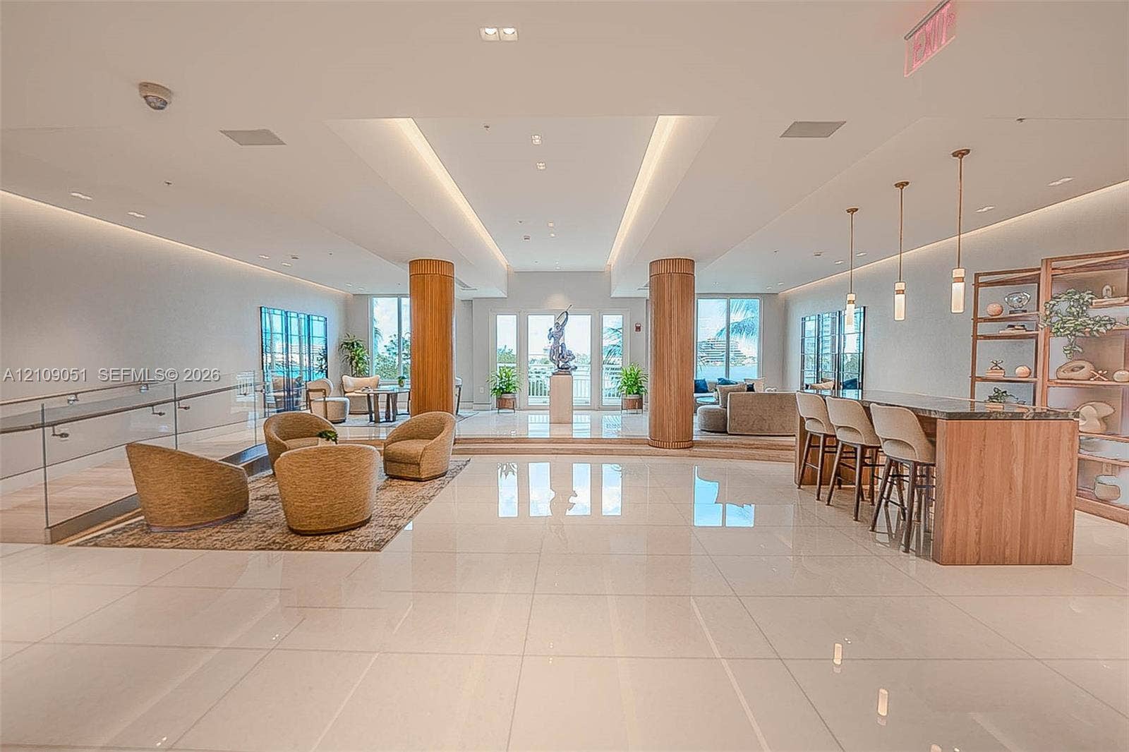 Open-concept interior featuring polished tile flooring, wood-clad structural columns, integrated cove lighting, and a built-in bar with matching cabinetry
