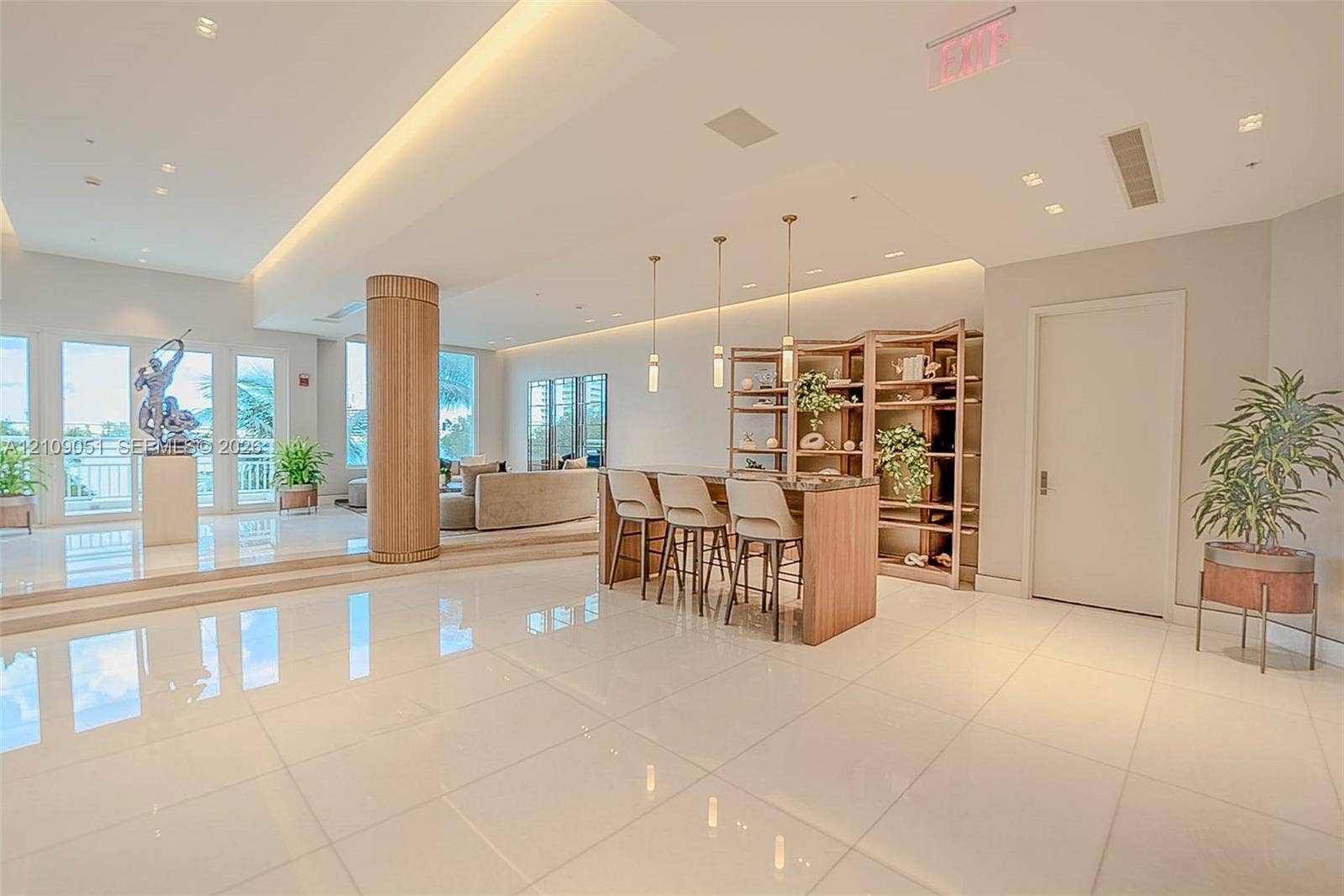 Spacious common area featuring polished tile flooring, tray ceilings with recessed lighting, a wood-wrapped structural column, and custom built-in shelving