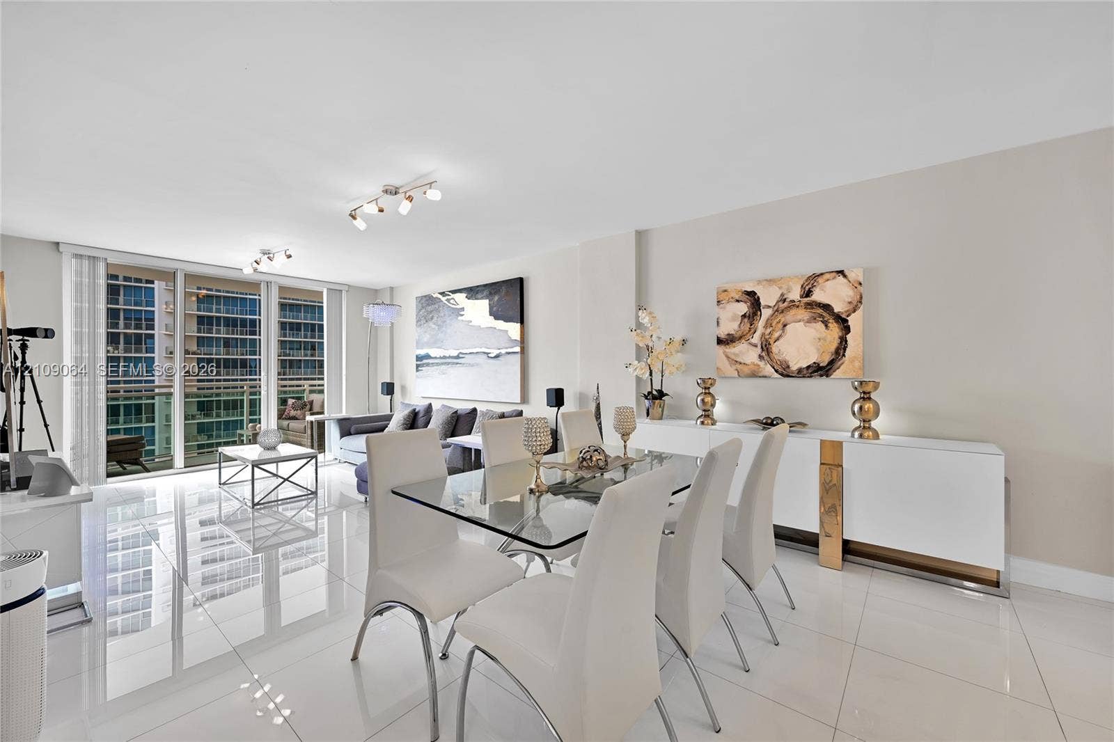 Open-concept interior featuring large-format polished tile flooring, floor-to-ceiling glass paneling, and adjustable track lighting