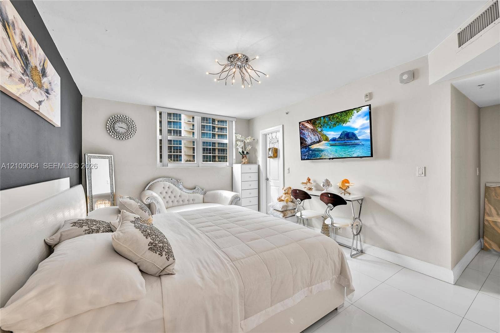 Bright room featuring white tile flooring, a dark charcoal accent wall, and a multi-arm contemporary ceiling light fixture