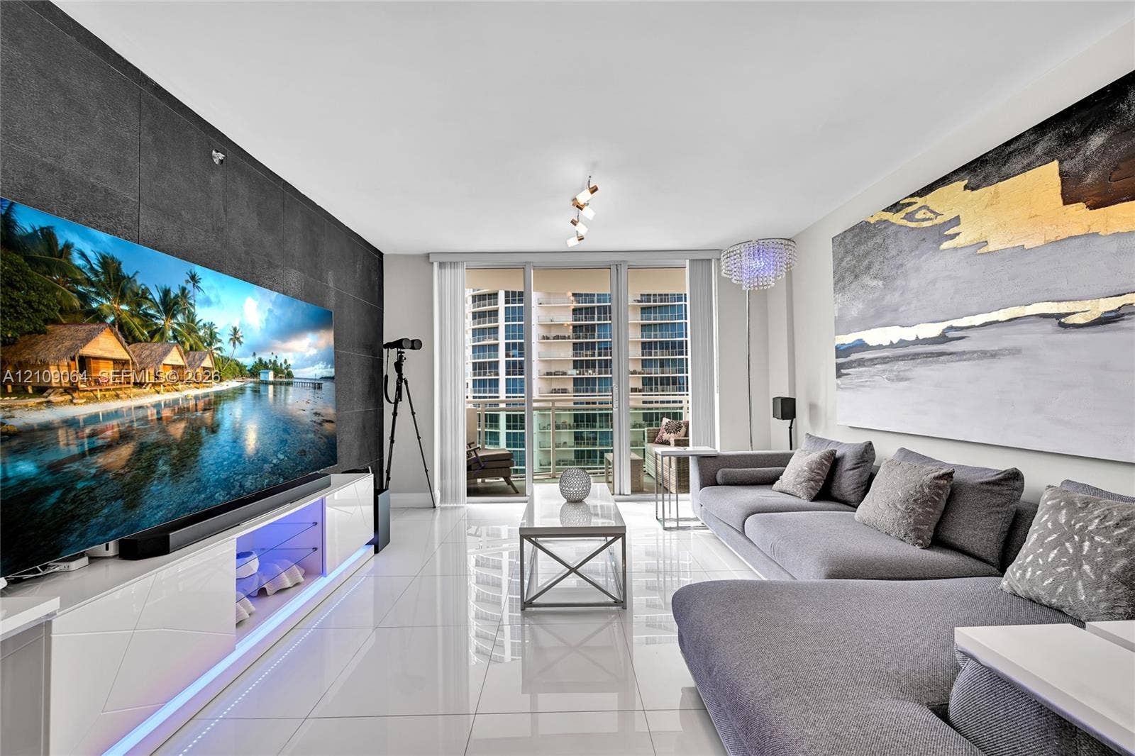 Large-format tile flooring, textured charcoal accent wall, glass balcony door system, and multi-directional track lighting