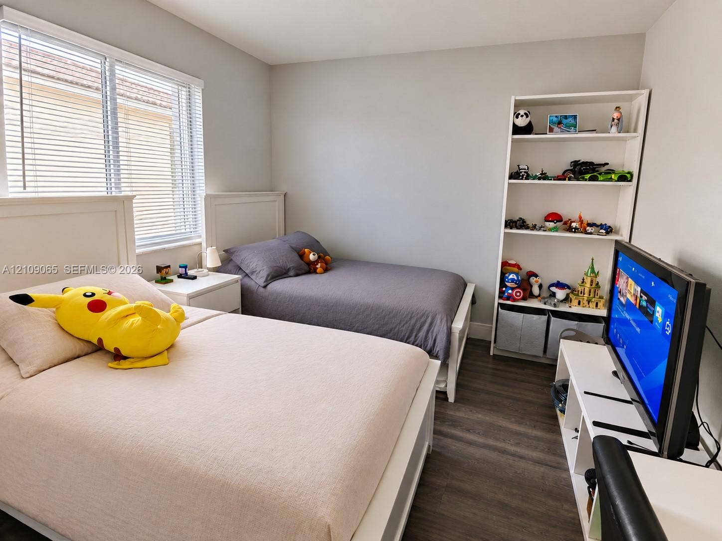 Room featuring wood-finish flooring, neutral wall paint, and multi-pane window with adjustable blinds