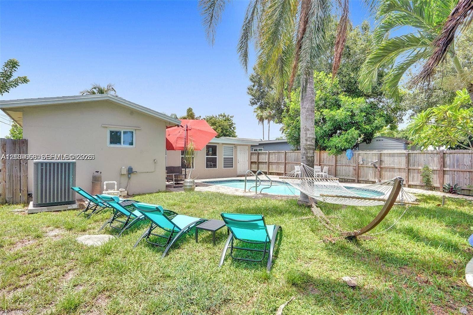 Backyard featuring an in-ground swimming pool, wood-fencing, and mature palm trees