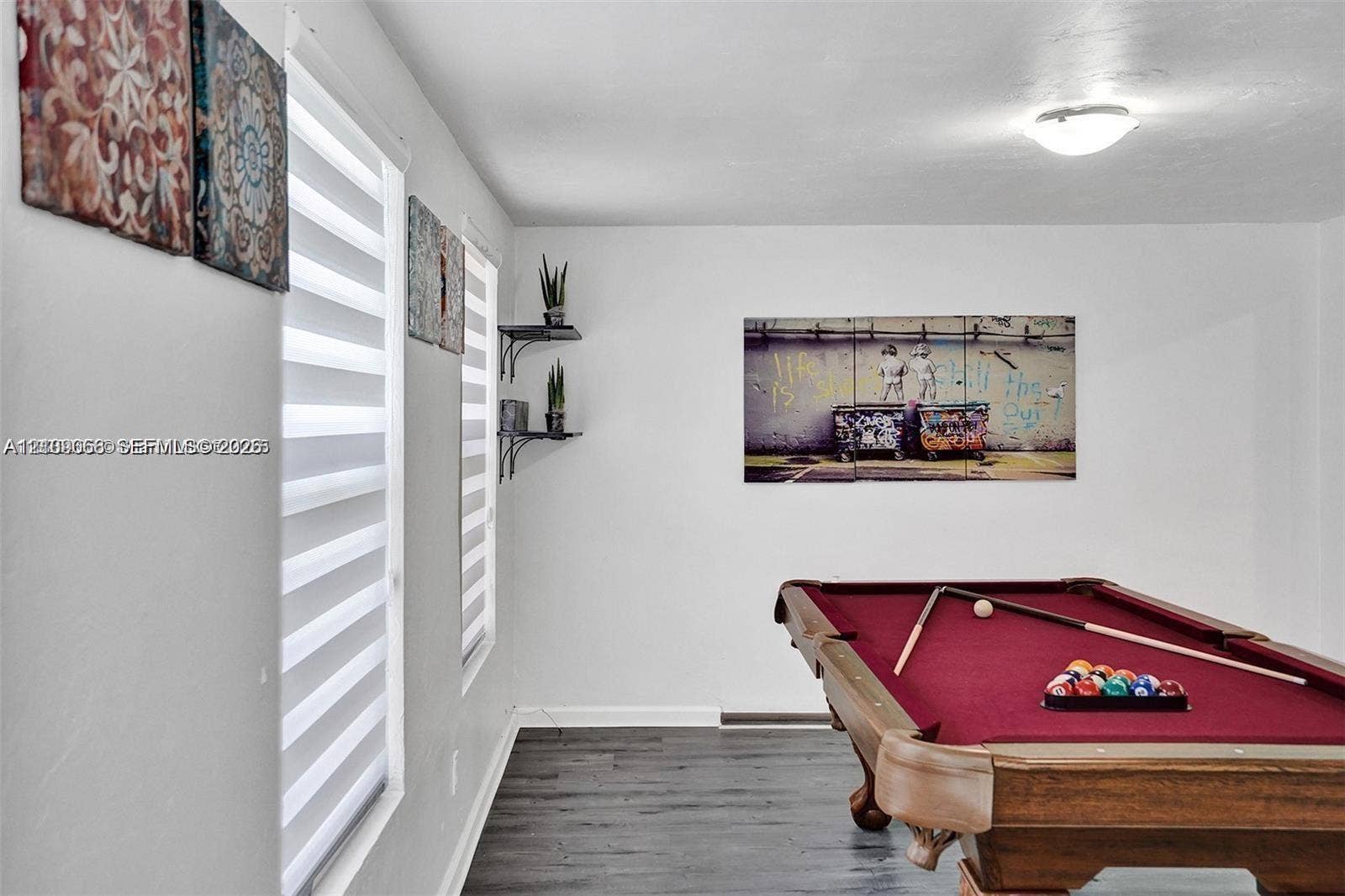 Wood-finish flooring, dual windows with integrated blinds, and two wall-mounted metal shelves