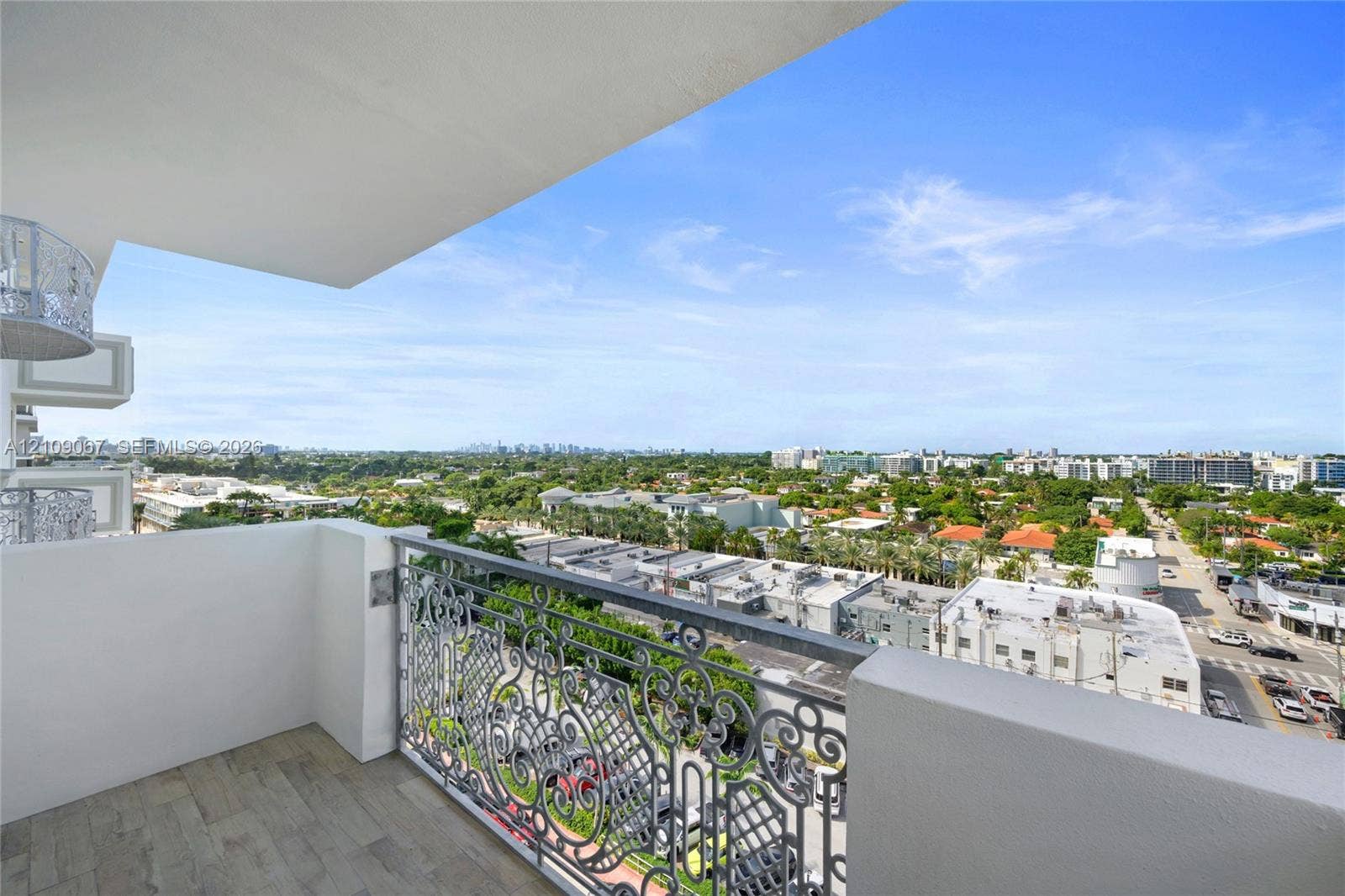 Private balcony featuring concrete flooring, intricate metal railings, and an expansive cityscape horizon
