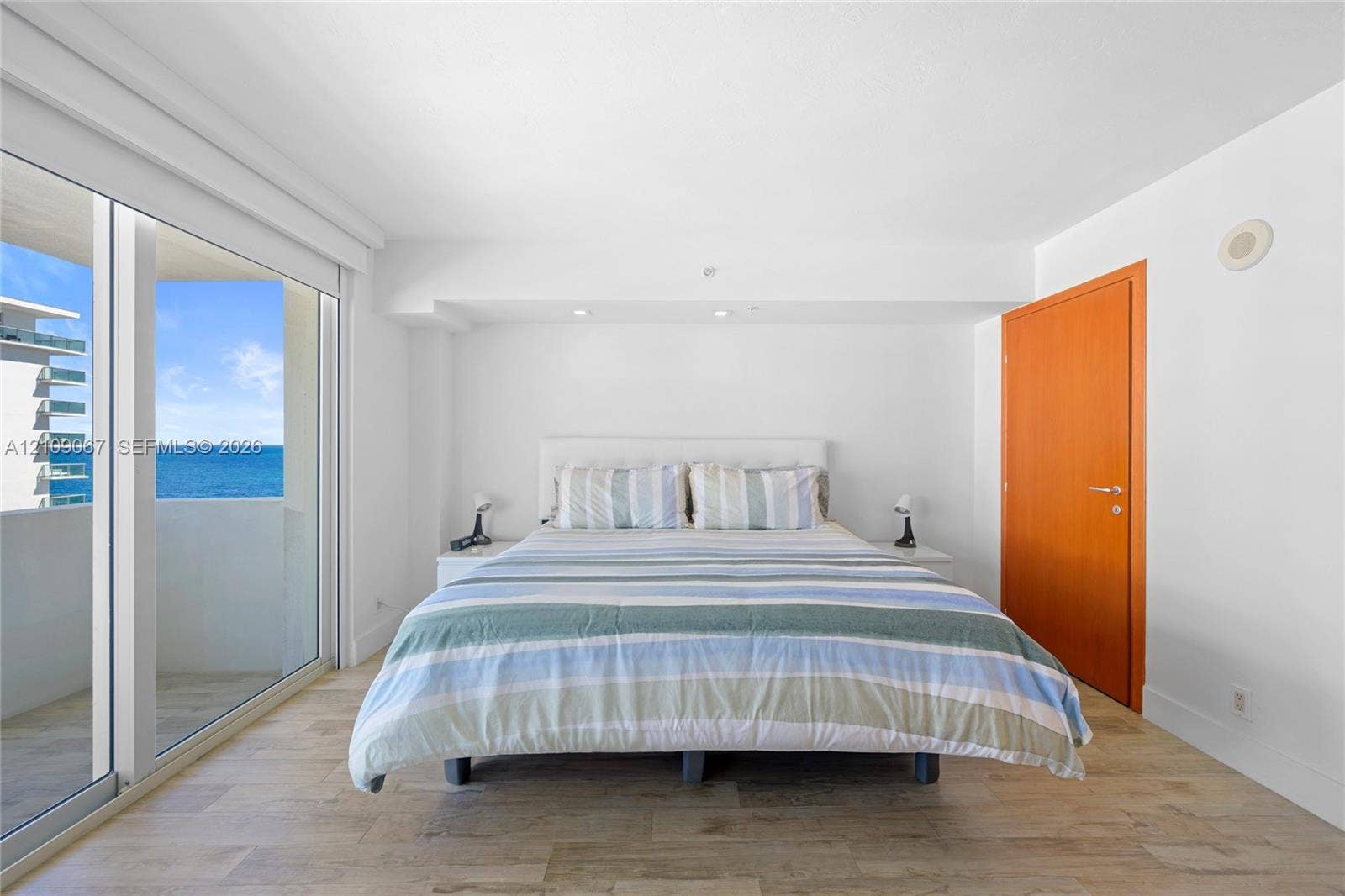 Wood-finish flooring, floor-to-ceiling sliding glass doors, recessed lighting, and a solid wood door