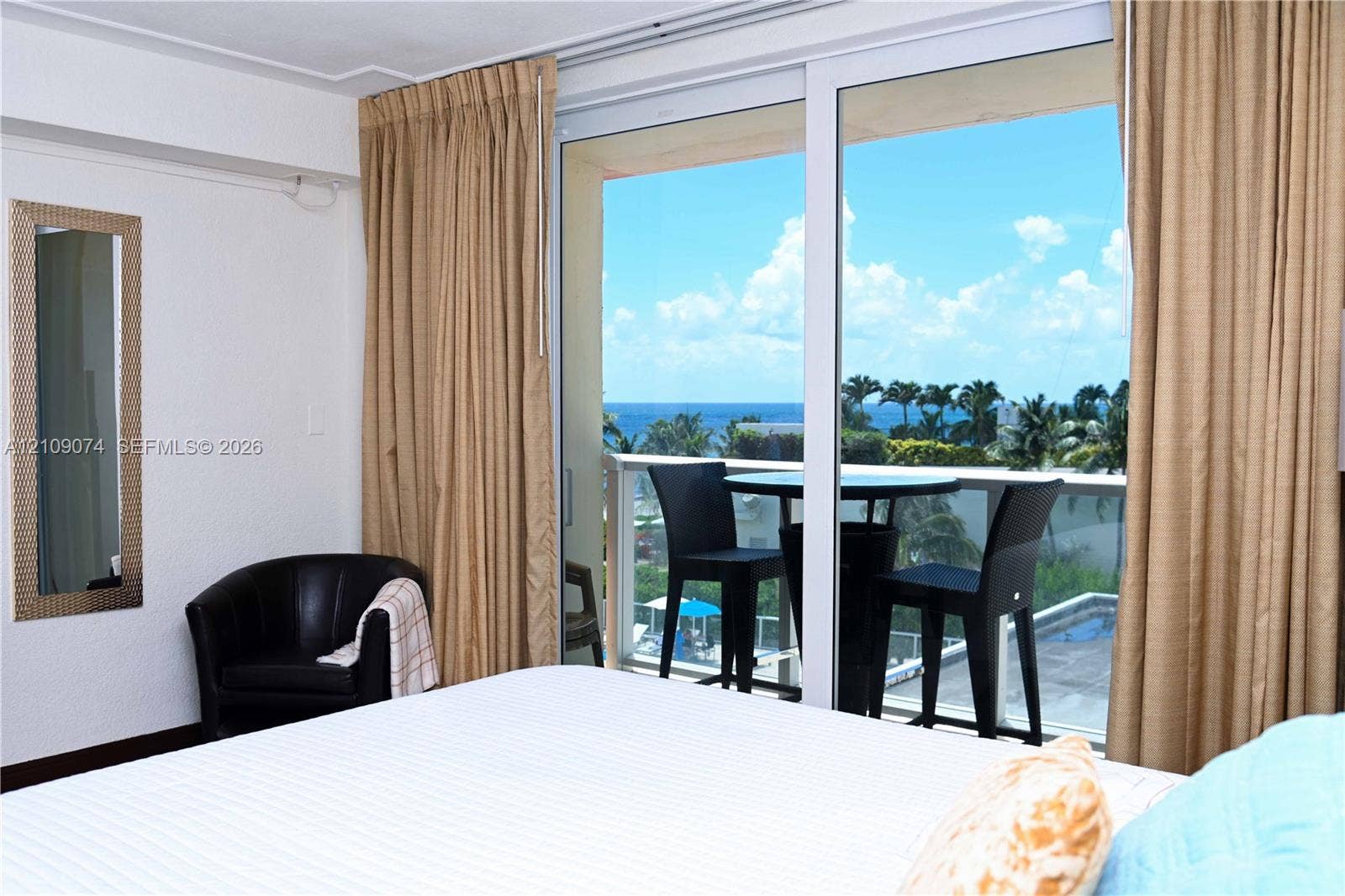 Floor-to-ceiling sliding glass door, private exterior balcony, and coastal horizon