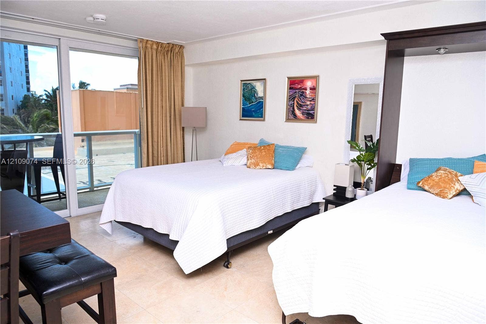 Neutral-toned stone flooring, sliding glass door with access to a private balcony, and built-in cabinetry