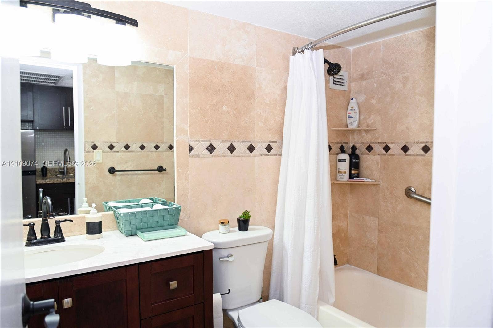 Bathroom featuring stone tile walls with decorative inlay, dark wood-finish cabinetry, a white countertop with integrated sink, and an oil-rubbed bronze faucet