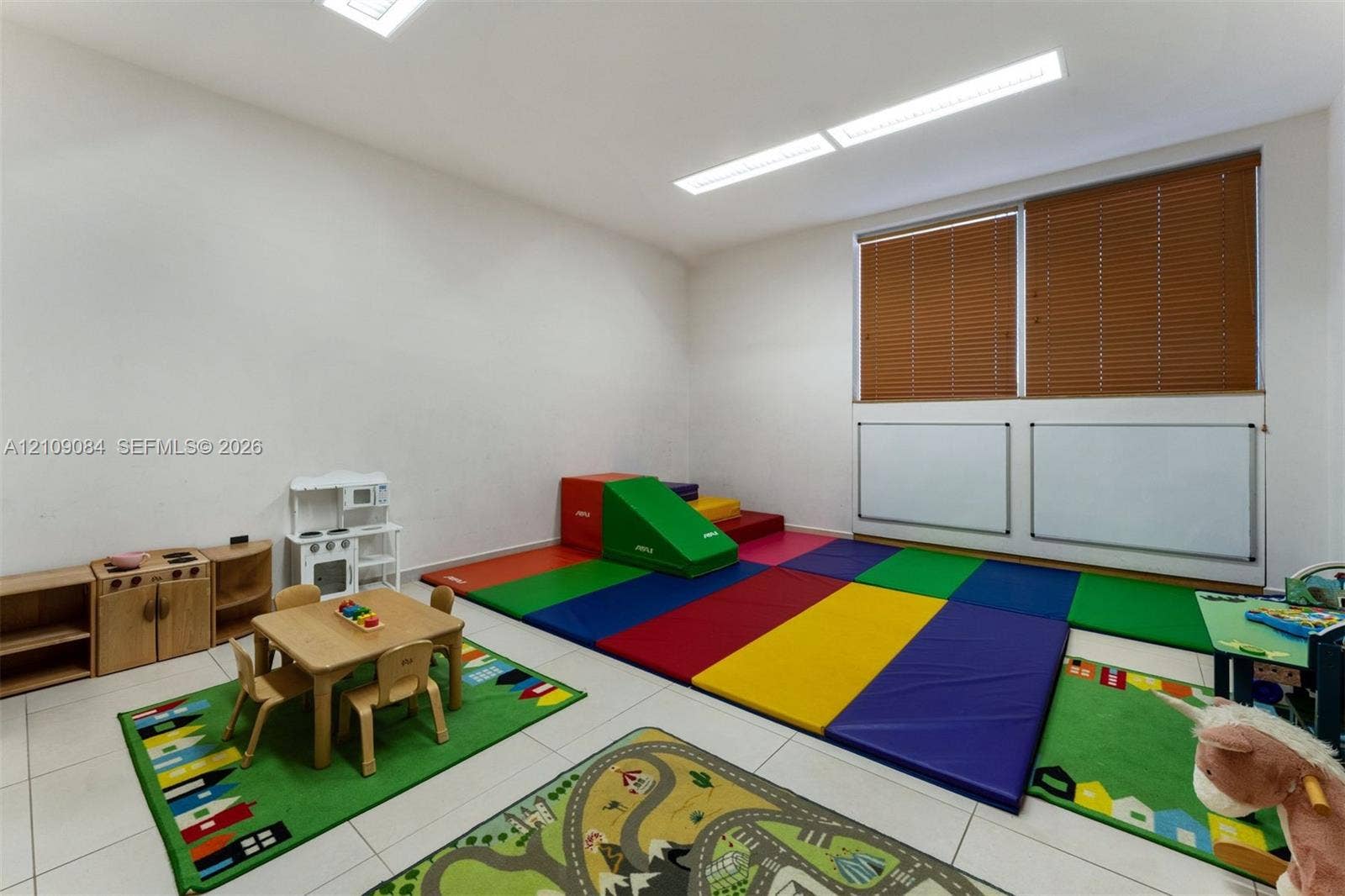 Interior room featuring large-format tile flooring, recessed panel lighting, and windows finished with horizontal blinds