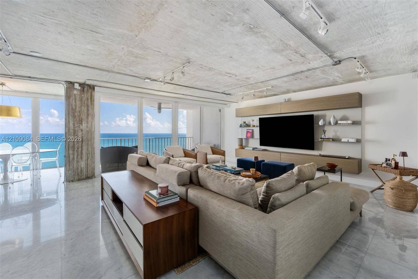 Exposed concrete ceiling with industrial-style surface-mounted track lighting, polished stone flooring, and high-gloss cabinetry