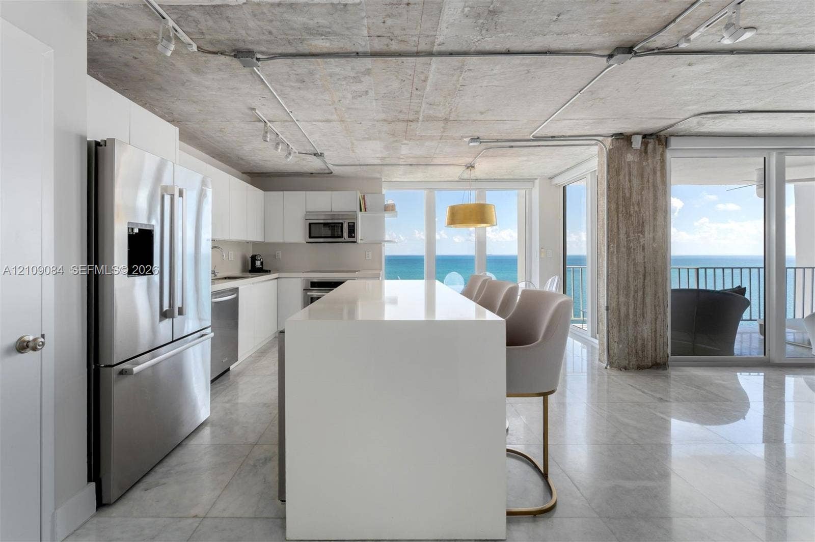Floor-to-ceiling windows, exposed concrete ceiling, industrial-style drum pendant lighting, polished stone-finish flooring, and exposed concrete structural pillar