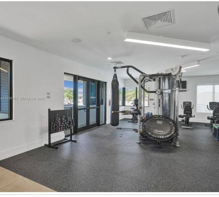 Fitness space featuring durable rubberized flooring, recessed and linear LED lighting, and large windows with black frames