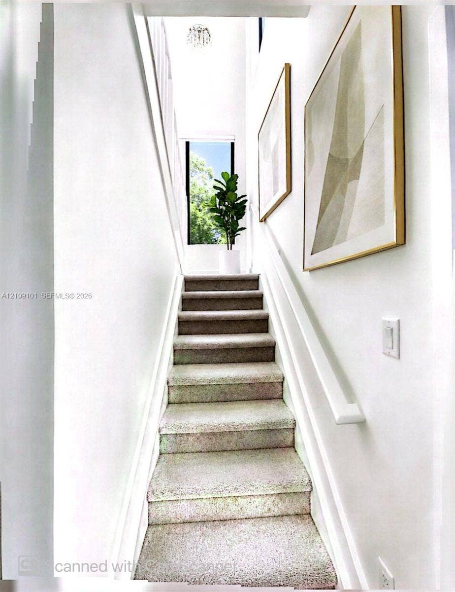 Staircase featuring wall-to-wall carpeting, high ceilings, a flush-mount light fixture, and a vertical window