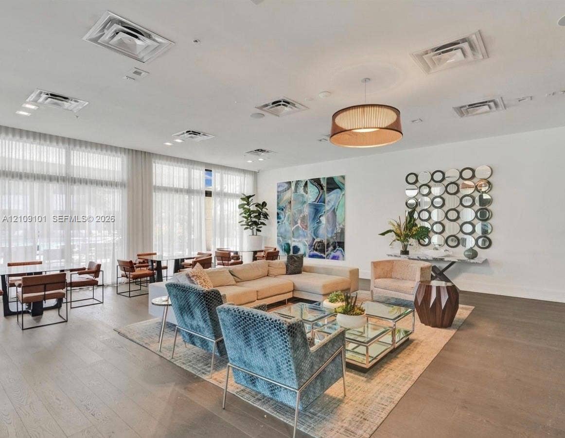 Expansive interior featuring floor-to-ceiling windows, wood-finish flooring, recessed ceiling lighting, and a circular drum pendant light fixture