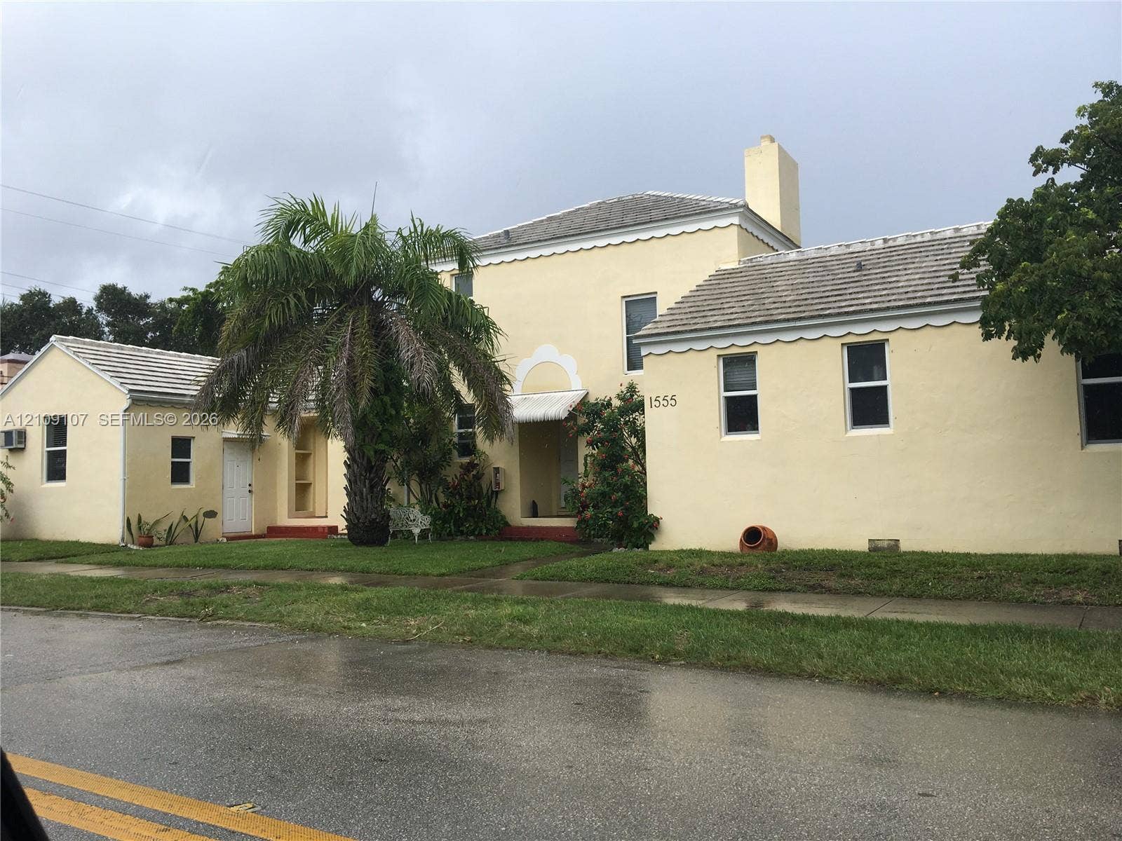Stucco exterior featuring scalloped roofline trim, a chimney, arched entryway detailing, and a tiled roof