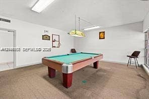 Interior space featuring neutral-toned carpeting, rectangular recessed overhead lighting, and a hanging geometric light fixture