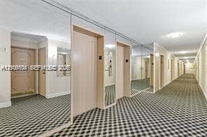 Hallway featuring wall-to-wall mirrored panels, patterned carpeting, and recessed ceiling lighting