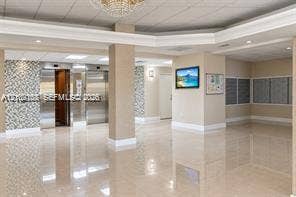 Lobby featuring polished tile flooring, metallic elevators with decorative tile surrounds, recessed lighting, and a tiered crystal chandelier