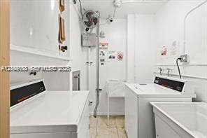 Utility room featuring side-by-side laundry appliances, a built-in utility sink, and stone-finish flooring