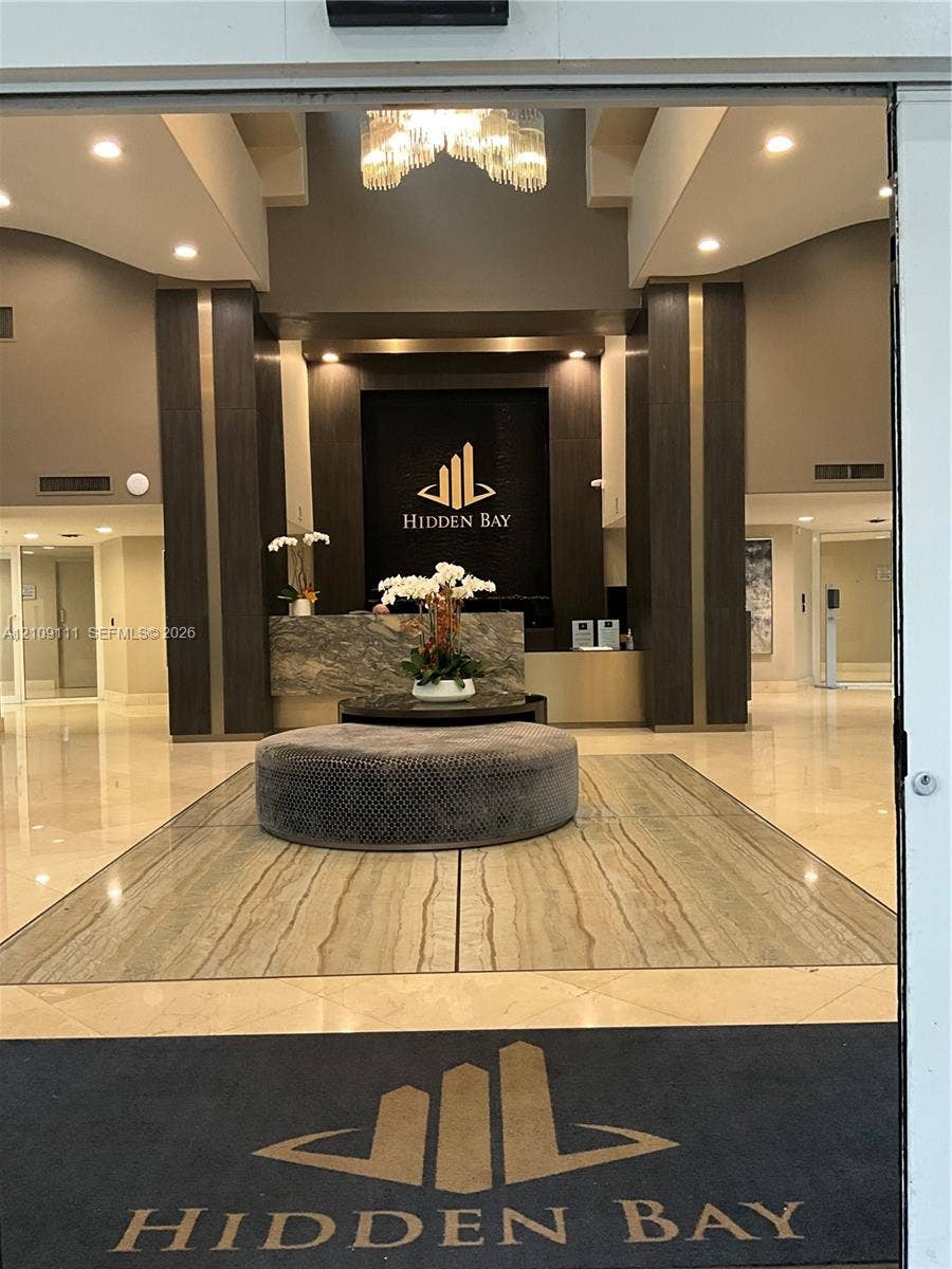 3370 Hidden Bay Drive, #801, Aventura, FL 33180 Lobby featuring polished stone flooring, recessed lighting, a stone-front reception desk, and decorative pendant lighting