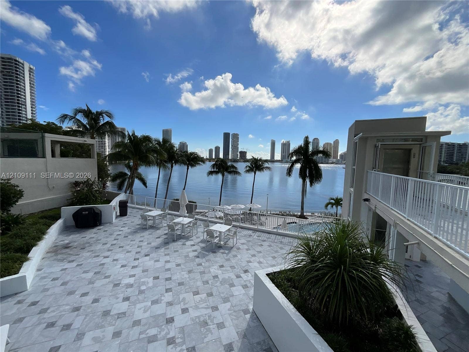 3370 Hidden Bay Drive, #801, Aventura, FL 33180 Expansive stone-paved terrace featuring white masonry planter boxes, perimeter metal railings, and elevated walkway access