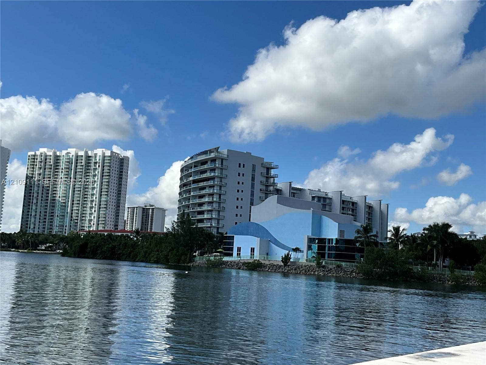 3370 Hidden Bay Drive, #801, Aventura, FL 33180 Waterfront location featuring a concrete bulkhead, high-rise architectural structures, and lush tropical vegetation
