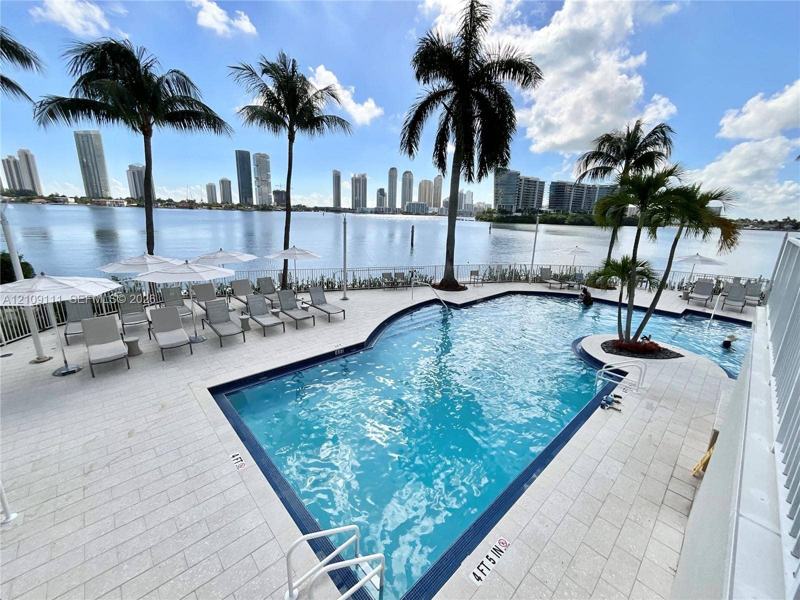 3370 Hidden Bay Drive, #801, Aventura, FL 33180 In-ground swimming pool with stone-tile decking, metal safety railing, and surrounding palm trees