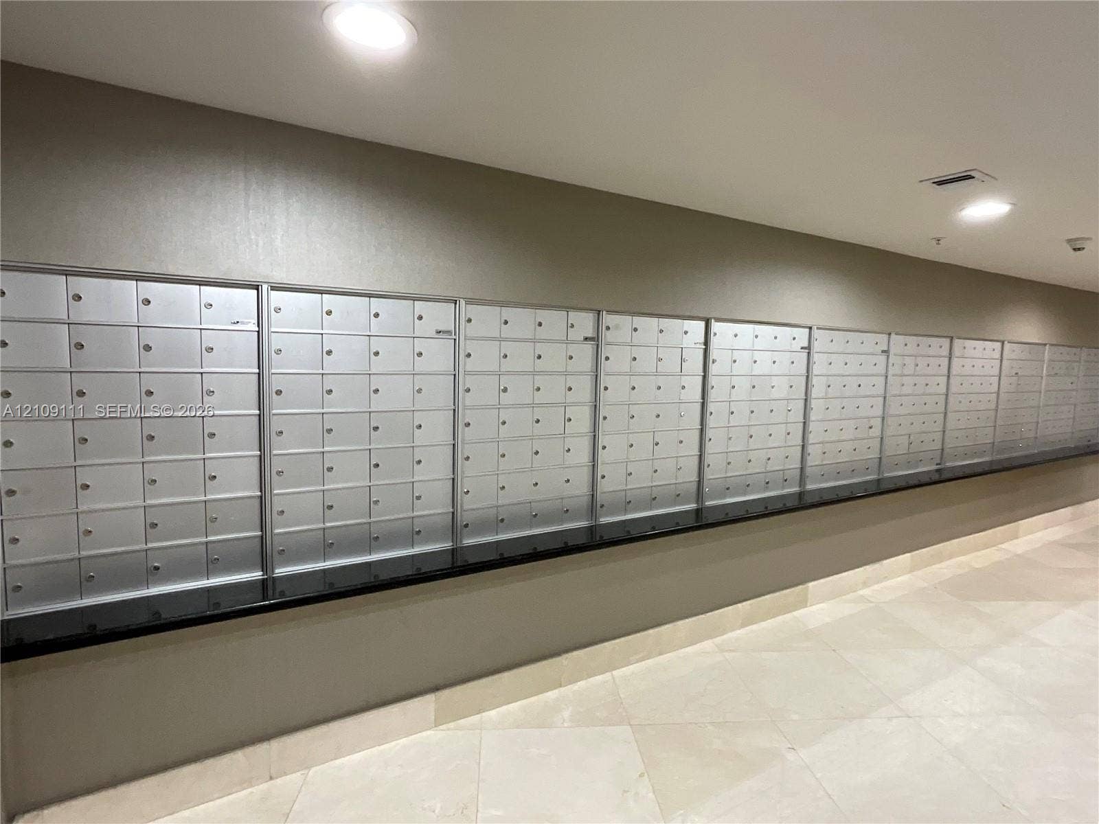 3370 Hidden Bay Drive, #801, Aventura, FL 33180 Wall-mounted metallic mailbox bank with a black solid surface counter and light-toned tile flooring