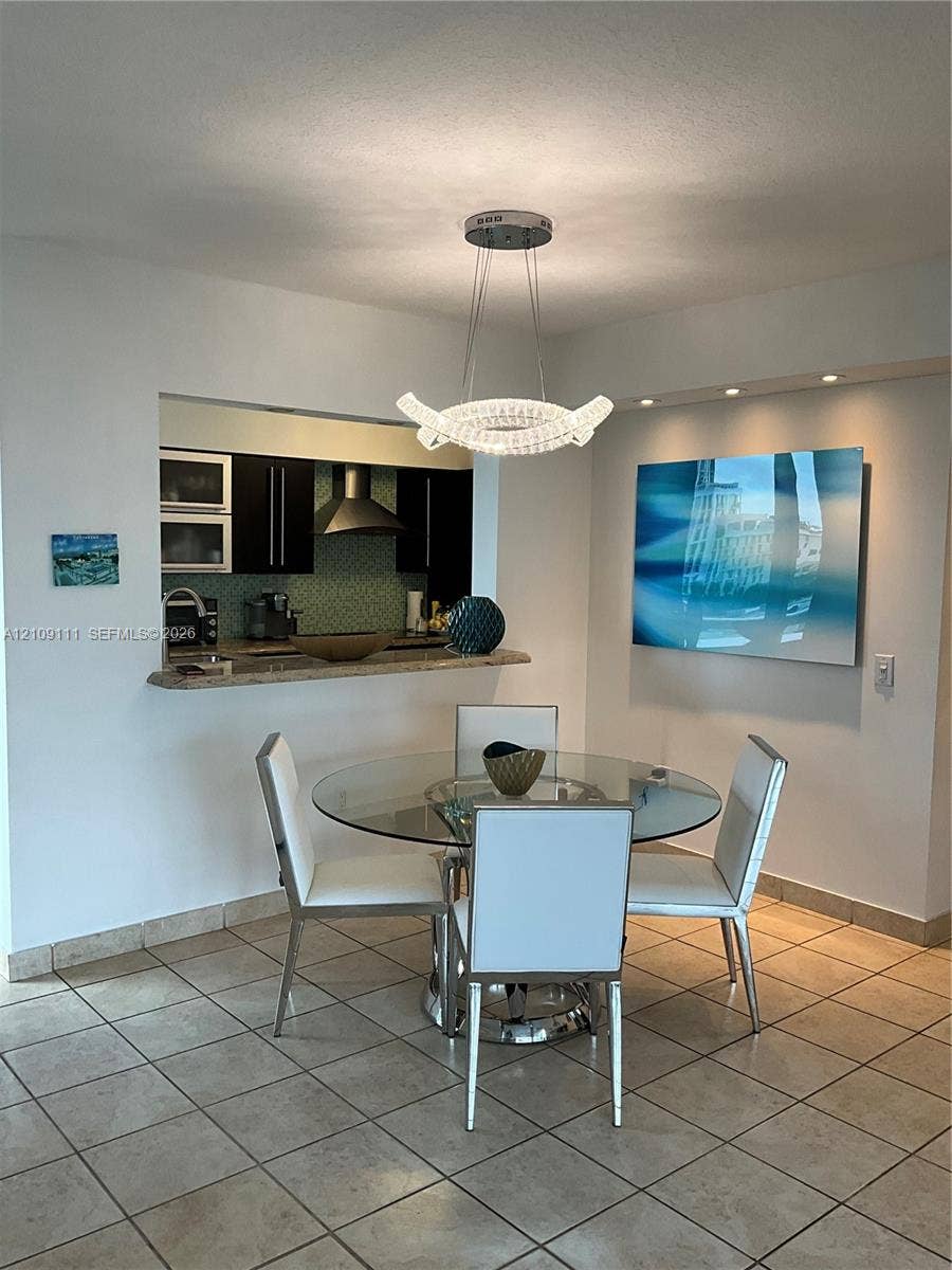 3370 Hidden Bay Drive, #801, Aventura, FL 33180 Modern crystal chandelier, stone-surfaced breakfast bar, recessed ceiling lighting, and tile flooring