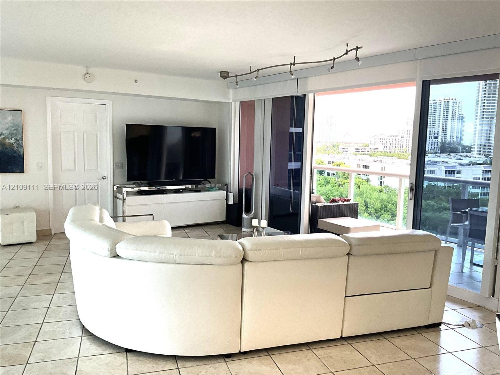 3370 Hidden Bay Drive, #801, Aventura, FL 33180 Large tile flooring, track lighting, and floor-to-ceiling sliding glass doors opening to a private balcony